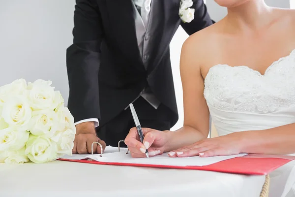 Sección media de una joven pareja firmando contrato de boda — Foto de Stock