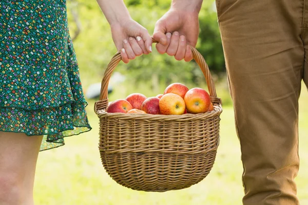 Корзина с яблоками, которую несет молодая пара — стоковое фото