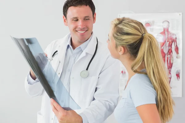 Fröhlicher Arzt zeigt einem Patienten etwas auf dem Röntgenbild — Stockfoto