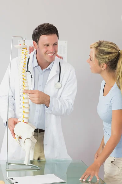 Médico alegre mostrando a um paciente algo no modelo de esqueleto — Fotografia de Stock