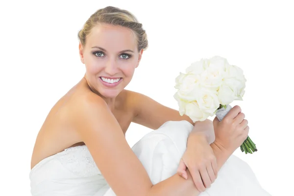 Happy blonde bride sitting on floor while holding a bouquet — Stock Photo, Image