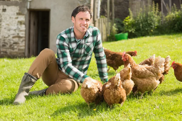 Jonge man voeding zijn kippen glimlachen op camera — Stockfoto