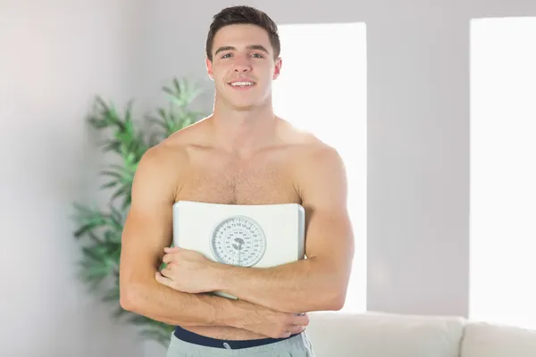 Confident smiling handsome man holding scales — Stock Photo, Image