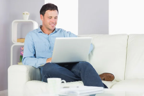 Content casual man sitting on couch using laptop — Stock Photo, Image