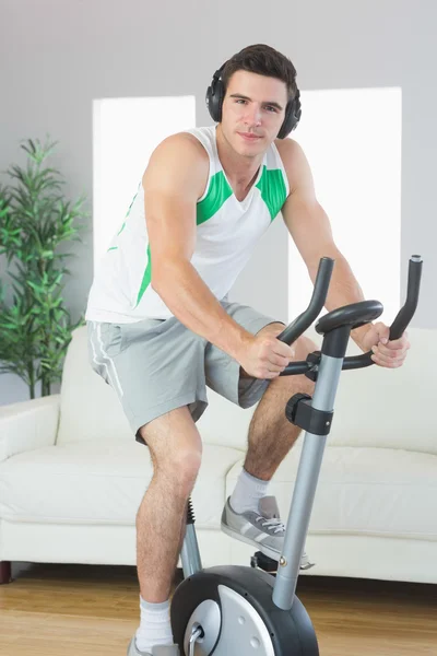 Content handsome man training on exercise bike listening to music — Stock Photo, Image