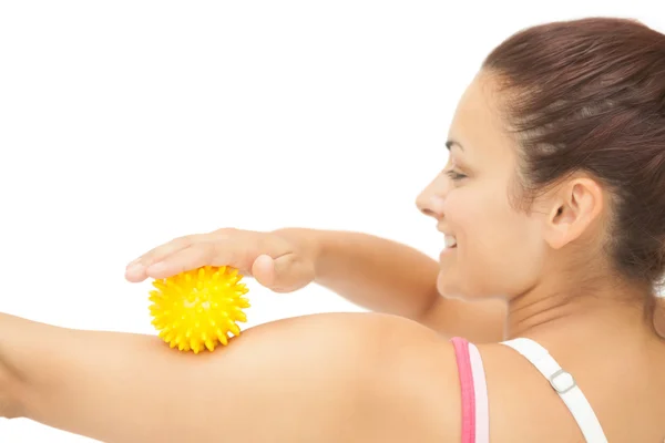 Fröhliche sportliche Brünette berührt Arm mit gelbem Massageball — Stockfoto