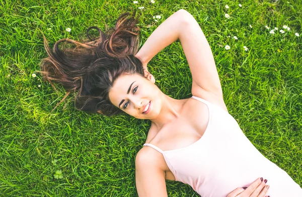 Pretty brunette woman lying on a lawn — Stock Photo, Image