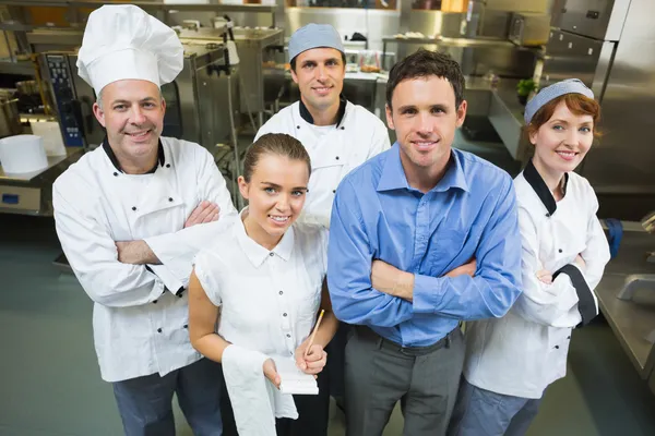 Guapo gerente posando con algunos chefs y camarera — Foto de Stock