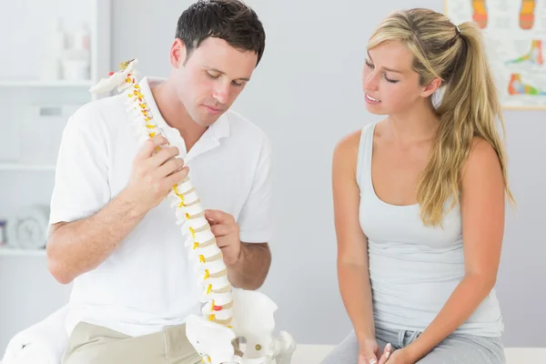 Smiling physiotherapist correcting patient doing exercise on exercise ball — Stock Photo, Image