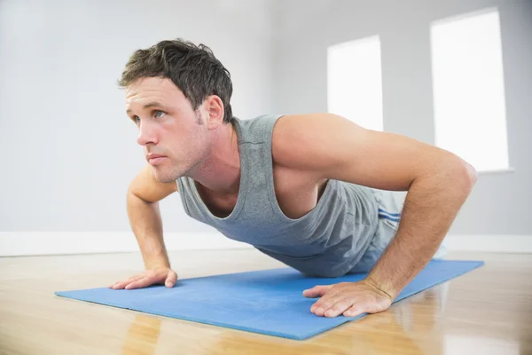 Attraente uomo sportivo facendo flessioni su tappetino blu — Foto Stock