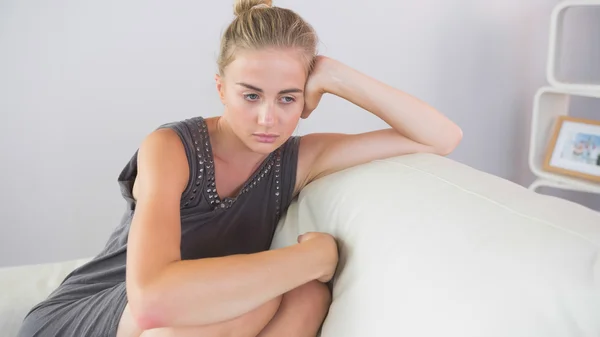Casual worried blonde sitting on couch — Stock Photo, Image