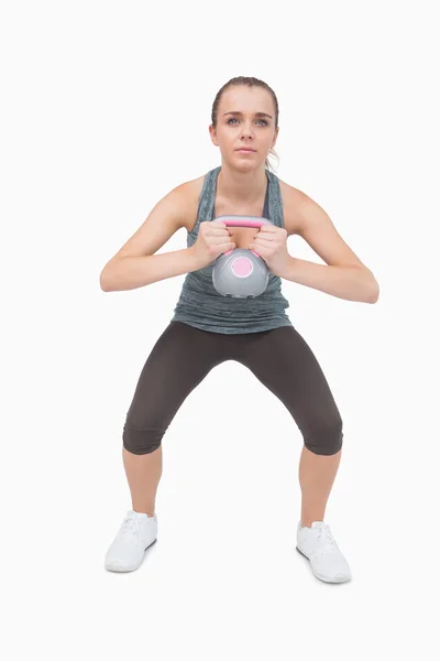 Jonge vrouw opleiding van haar lichaam met een waterkoker bell — Stockfoto