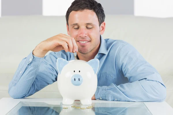 Inhoud casual man munt aanbrengend piggy bank — Stockfoto