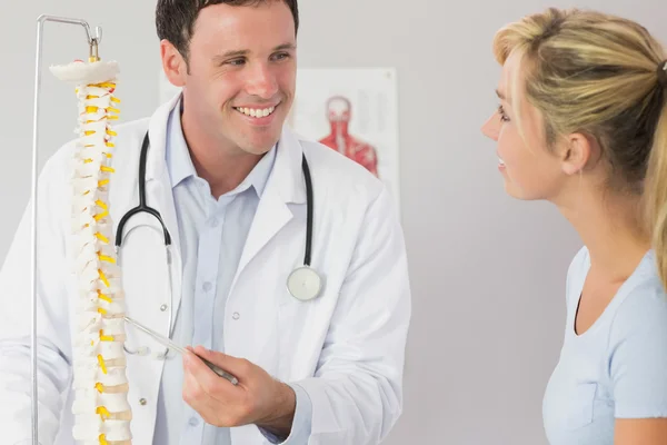 Suerte doctor mostrando a un paciente algo en esqueleto modelo — Foto de Stock