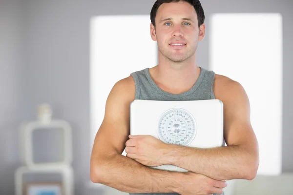 Sporty smiling man holding a scale — Stock Photo, Image