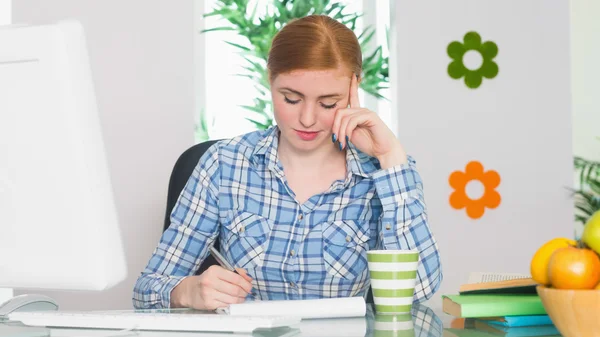 Mooie roodharige schrijven op haar Bureau — Stockfoto