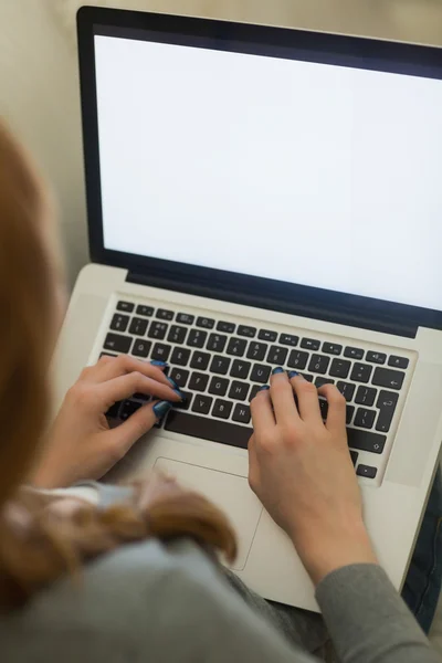 Ruiva sentada no sofá usando seu laptop à noite — Fotografia de Stock