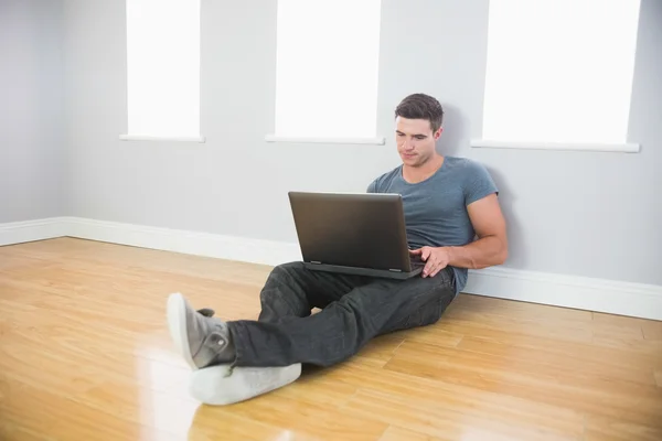 Tranquilo hombre guapo apoyado contra la pared usando el ordenador portátil —  Fotos de Stock