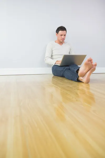 Casual homem atraente encostado à parede usando laptop — Fotografia de Stock