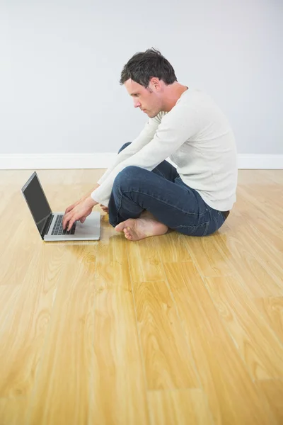 Hombre atractivo casual sentado en el suelo usando el ordenador portátil — Foto de Stock