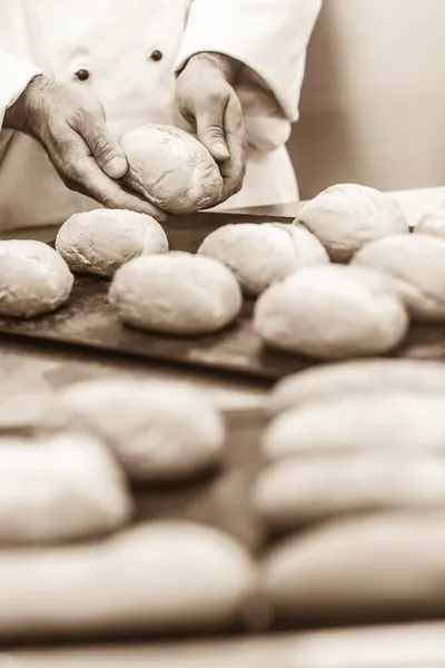 Мужчина пекарь формирует несколько рулонов — стоковое фото