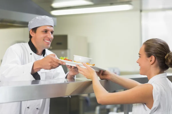 Jonge gelukkig chef-kok een plaat overhandigen aan de serveerster — Stockfoto