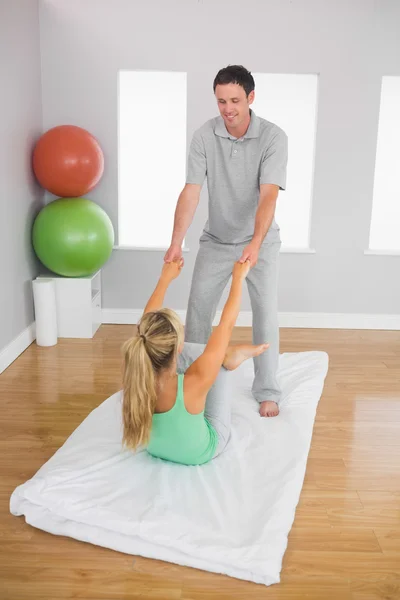 Fisioterapeuta sonriente ayudando al paciente a hacer ejercicio — Foto de Stock