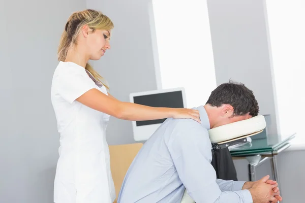 Masseuse treating shoulders of client in massage chair — Stock Photo, Image