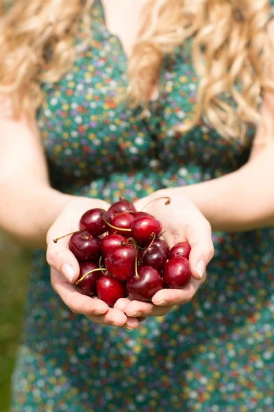 Close up of a blonde woman holding some cherries — Stock Photo, Image