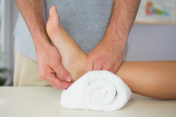 Physiotherapist checking patients foot on towel — Stock Photo, Image