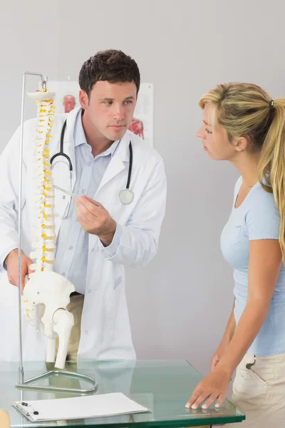 Ήρεμη γιατρός που δείχνει έναν ασθενή κάτι σε μοντέλου σκελετού — Φωτογραφία Αρχείου
