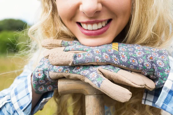 Vrolijke blonde vrouw leunend op een schop tuinieren handschoenen — Stockfoto