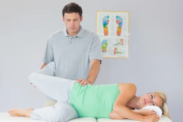 Handsome physiotherapist manipulating patients leg — Stock Photo, Image