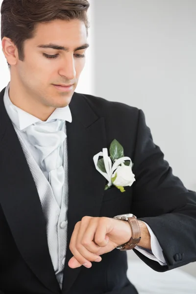 Schöner Bräutigam schaut auf die Uhr — Stockfoto