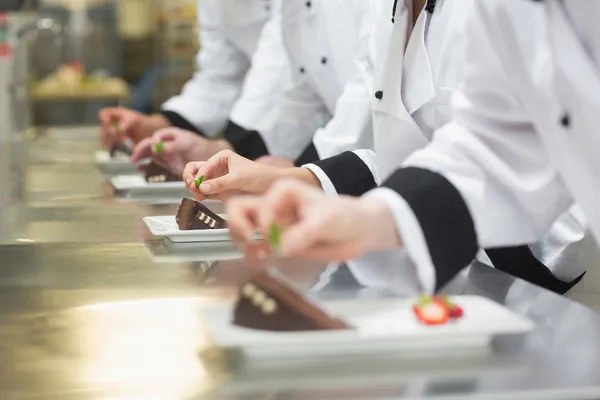 Équipe de chefs garnissant des assiettes à dessert — Photo