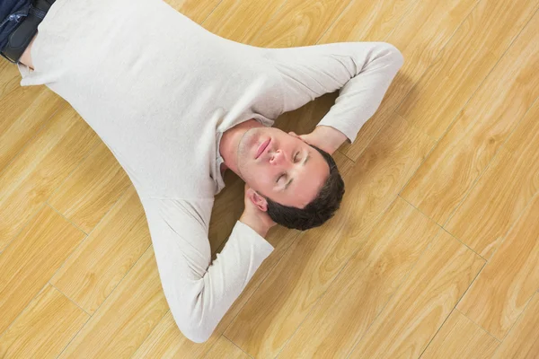 En rolig mann som ligger på gulvet med lukkede øyne – stockfoto