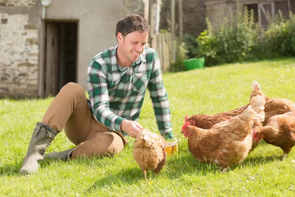 Jonge man voeding zijn kippen — Stockfoto