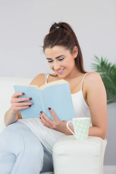 Geamuseerd leuke vrouw lezen van een boek — Stockfoto