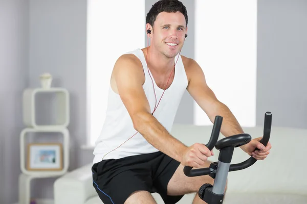 Sonriente deportista haciendo ejercicio en bicicleta y escuchando música — Foto de Stock