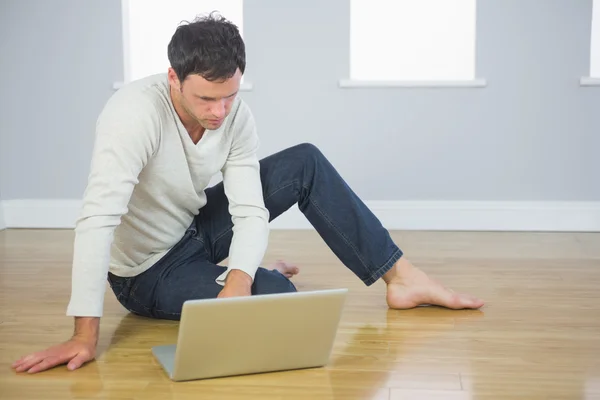 Casual good looking man sitting on floor using laptop — Stock Photo, Image