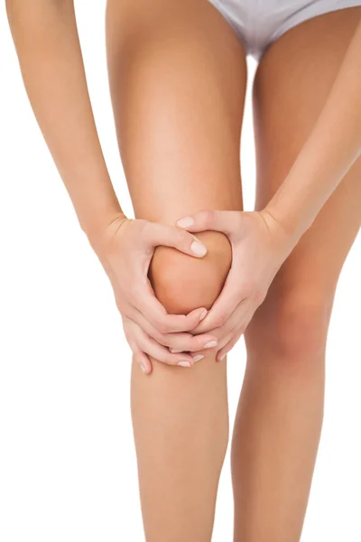 Szczupła, młoda kobieta, dotykając jej rannych kolana — Zdjęcie stockowe
