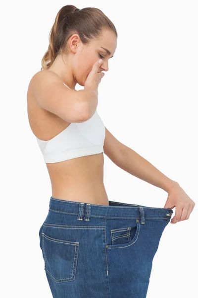 Verbaasd slank jonge vrouw dragen van te grote jeans — Stockfoto