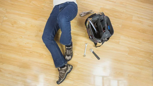 Close up of male legs lying on floor next to tools — Stock Photo, Image