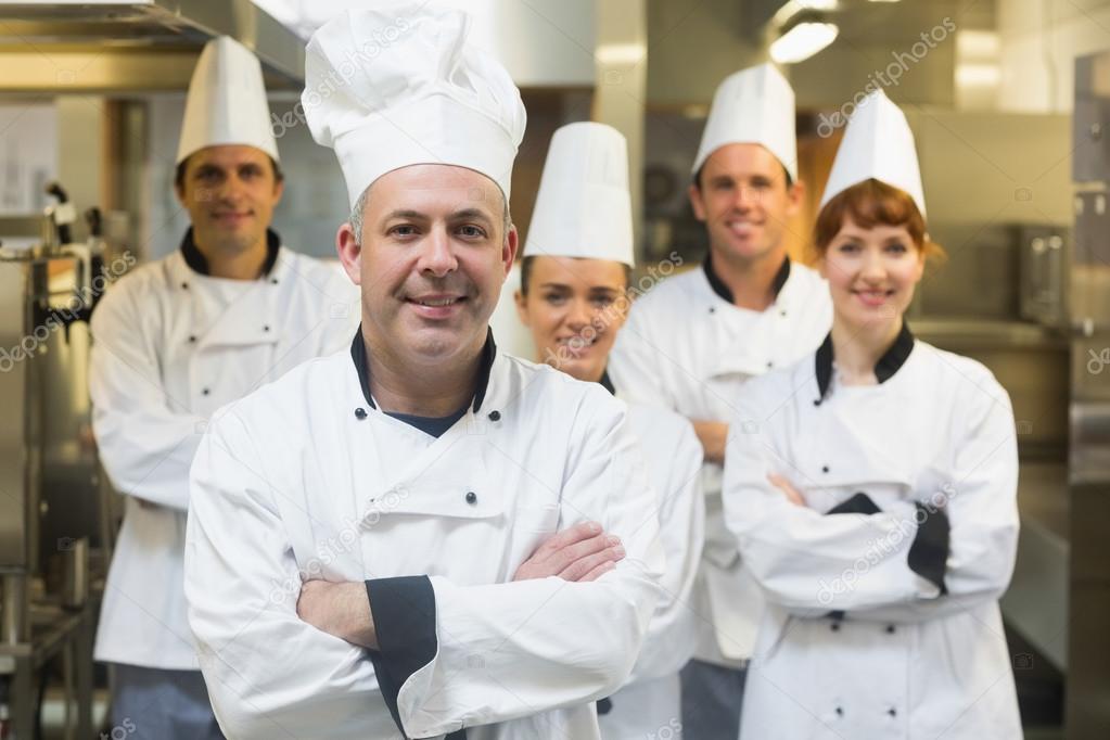 Five chefs wearing uniforms posing in a kitchen — Stock Photo