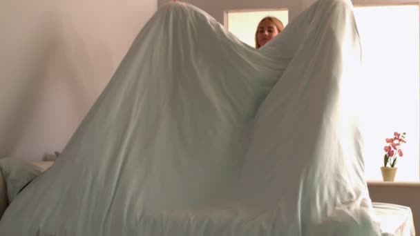 Attractive blonde giving the comforter a shake — Stock Video