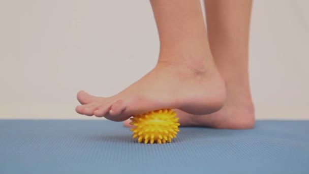 Girl using yellow massage ball on her foot — Stock Video