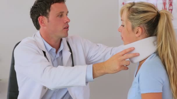 Доктор прикрепляет шейный корсет к пациенту — стоковое видео