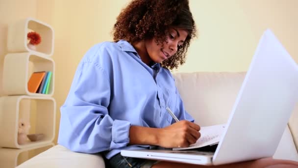 Wunderschöne glückliche Studentin sitzt auf Couch studieren — Stockvideo