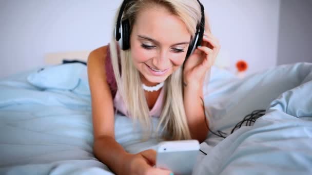 Attraktiva blonde lyssna på musik och liggande på sängen有吸引力的金发女郎听音乐和躺在床上 — 图库视频影像