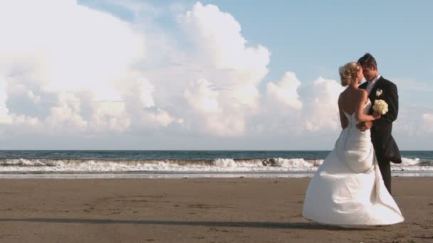 Привлекательная молодожёны целуются на пляже — стоковое видео